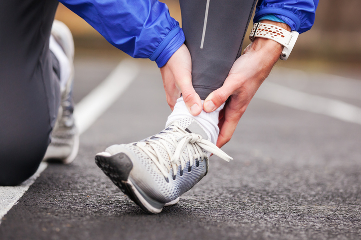 Cropped shot of a young man holding his ankle in pain while running.